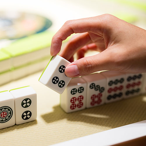 麻將抓牌：桌上已疊好麻將牌，由骰子骰出後，左方的玩家率先開門拿牌。