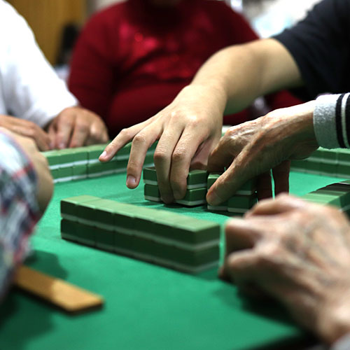 綠色桌布麻將桌，上面有背面是橘色麻將牌，以及散落的正面麻將牌以及骰子。